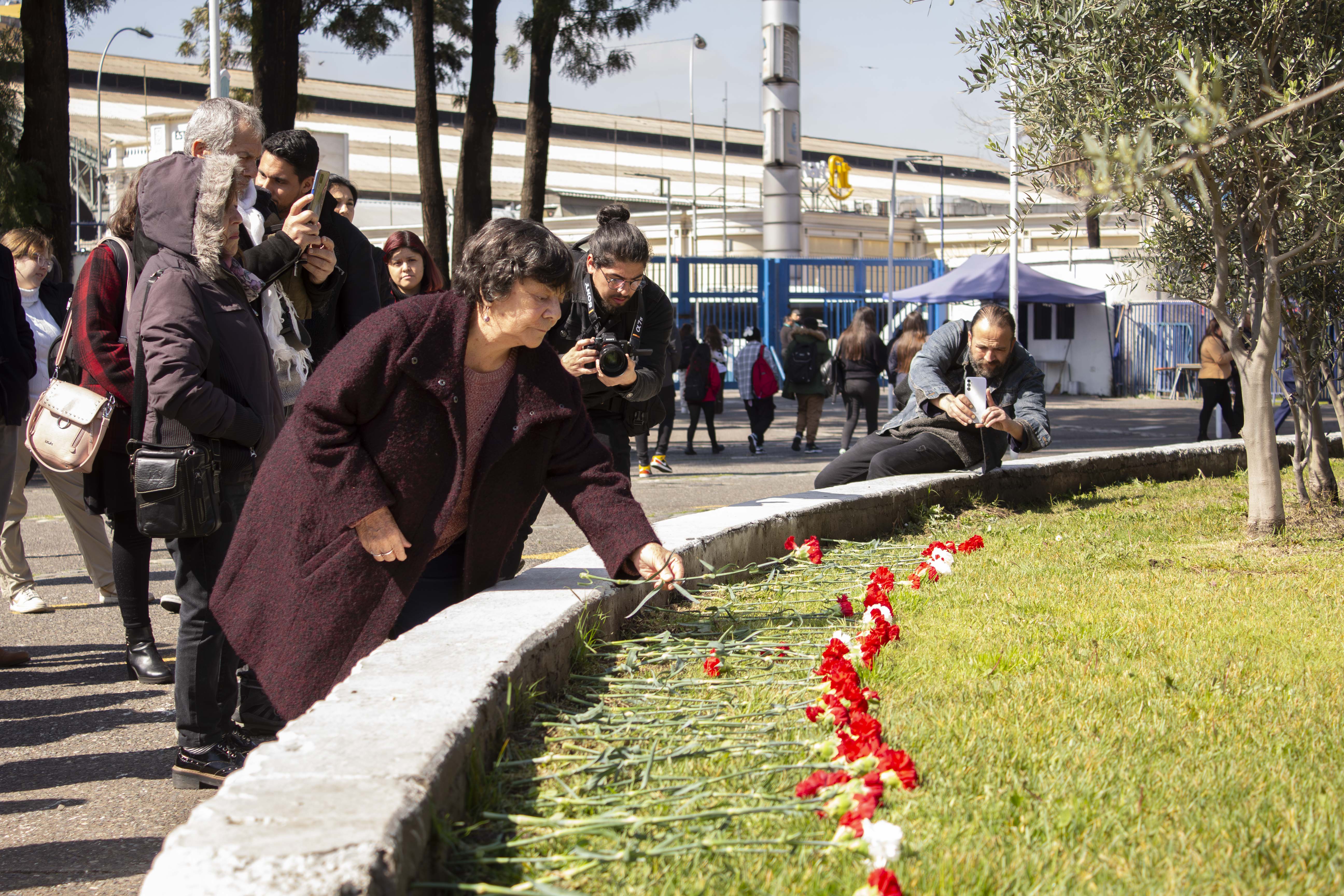 Alicia Lira, presidenta de la Agrupación de Familiares de Ejecutados Políticos, deposita un clavel frente al memorial de los desaparecidos de la UTE